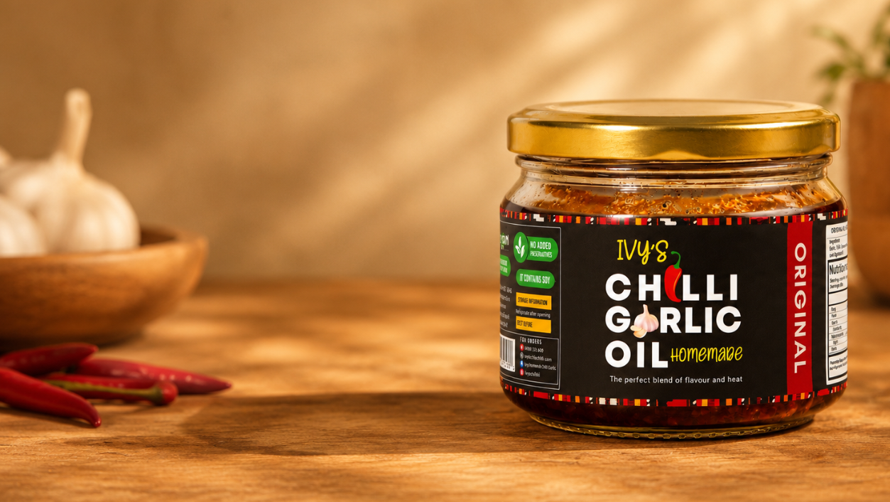 Jar of Ivy's Chilli Garlic Oil on a wooden surface with garlic and chilies in the background.